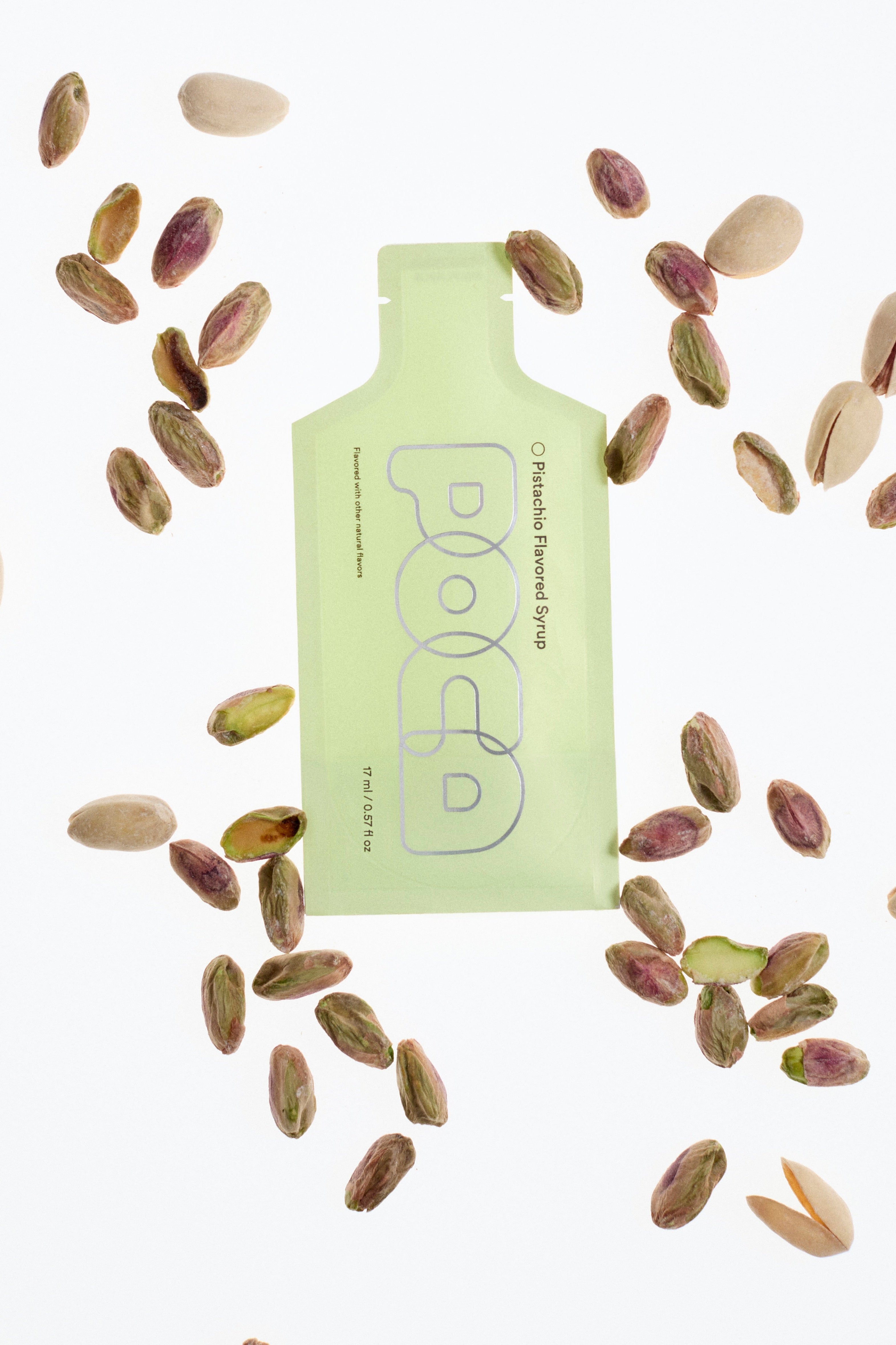 Light green 'POCA' surrounded by scattered pistachios on a white background.