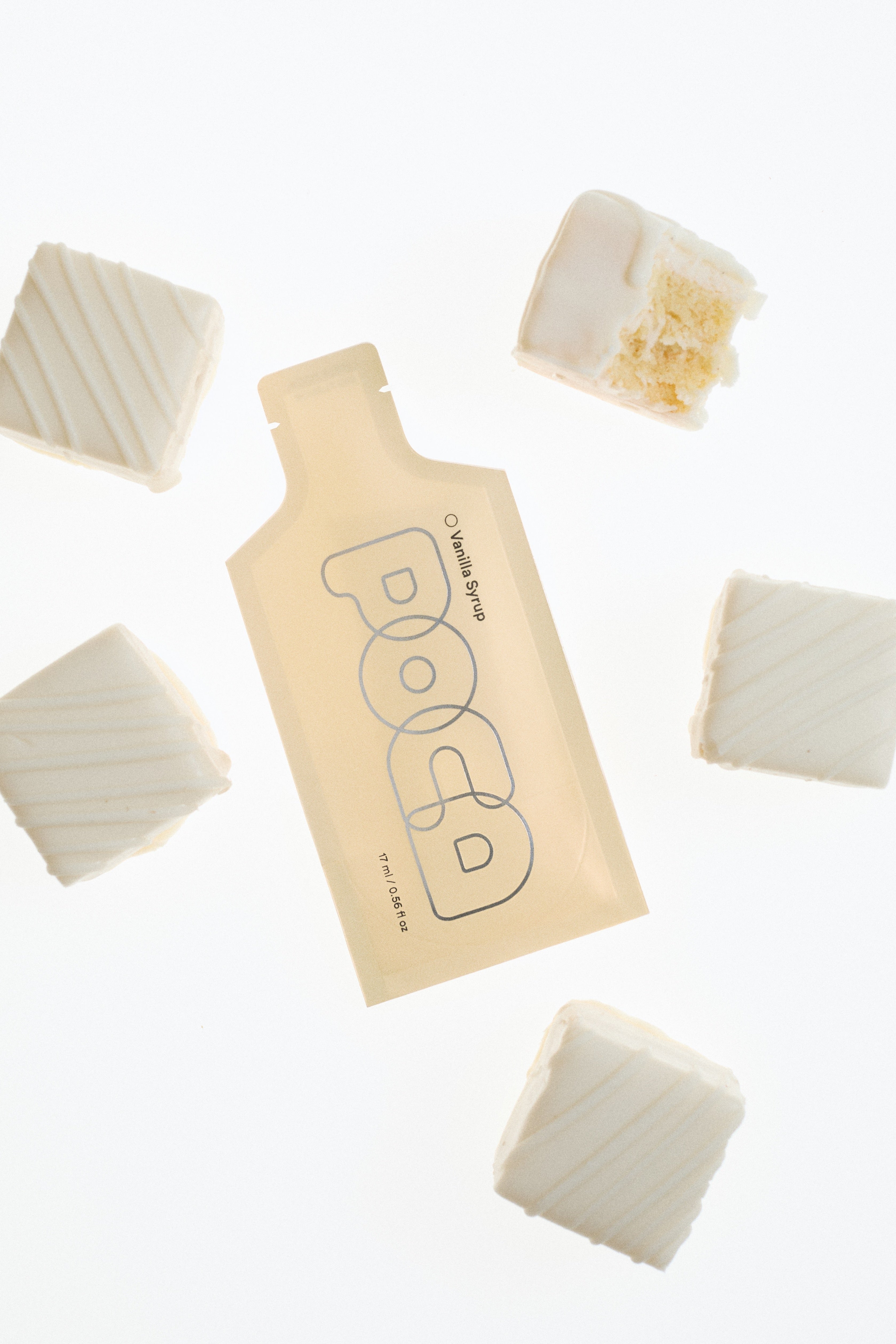 Vanilla POCA with little cakes around it and one has a bite in it.