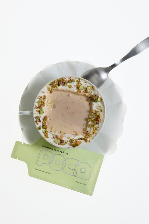 Small plate with dessert, spoon, and a green packet labeled 'POCA' on a white background.