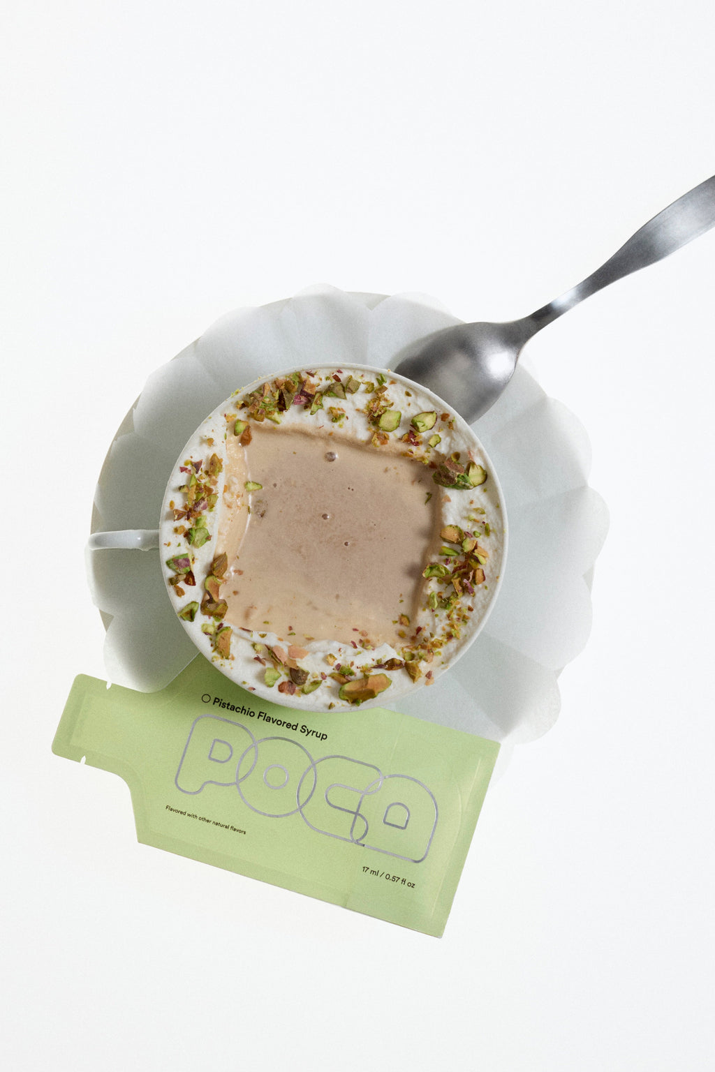 Small plate with dessert, spoon, and a green packet labeled 'POCA' on a white background.